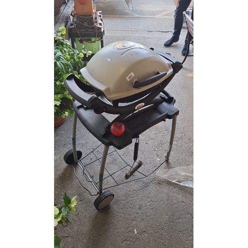 891 - Star lot : A Weber Baby Q portable gas barbecue grill. Features a durable design and easy mobility. ... 