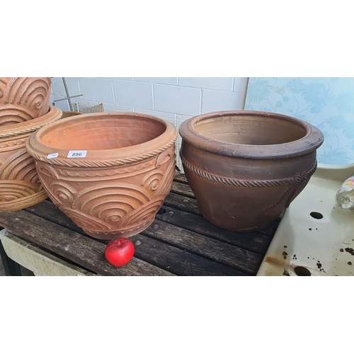 896 - Two large terracotta pots, one with classical relief patterns and the other with a simple braided de... 