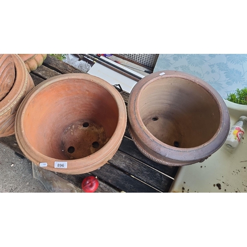 896 - Two large terracotta pots, one with classical relief patterns and the other with a simple braided de... 