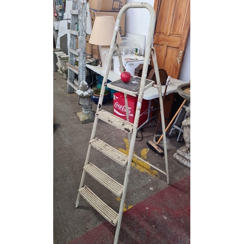 935 - A vintage metal step ladder with a high handle, providing stable support and utilitarian charm.