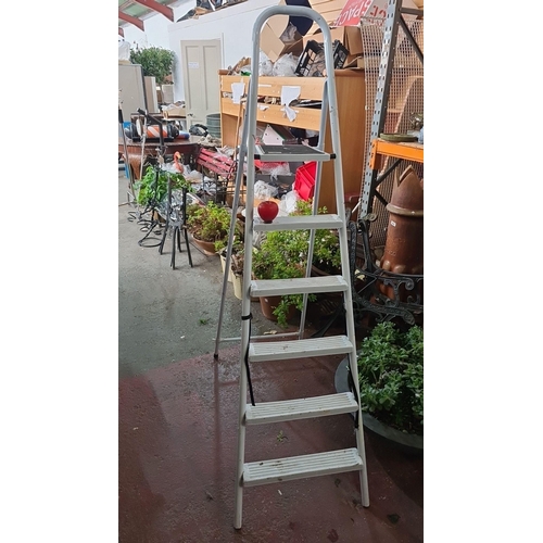 940 - A tall White five-step ladder with a sturdy frame.