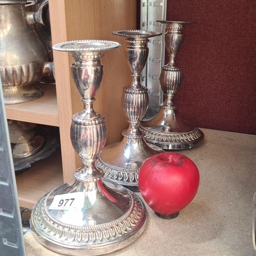 977 - Set of three silver-plated candlesticks featuring intricate detailing and beaded rims, elegant for a... 