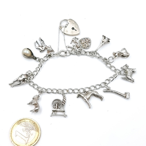 57 - A sterling silver charm bracelet (11 charms) set with padlock clasps and safety chain. Weight - 25.6... 