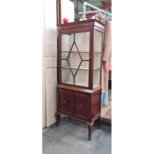 1002 - A Victorian glass fronted display cabinet with three internal shelves and two additional cupboards b... 