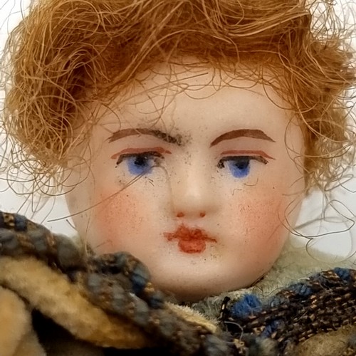 31 - An antique bisque miniature doll with natural hair with attractive clothing. Height - 8 cms.