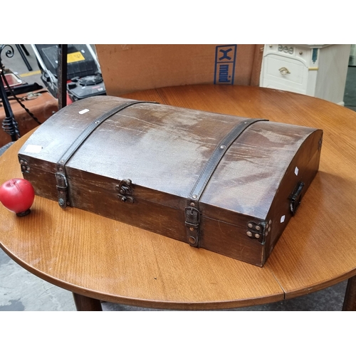 449 - A domed wooden low profile storage trunk with leather strap detail and metal hardware.