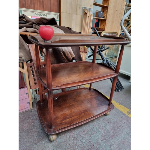 479 - An enviable three tier Ercol wooden drinks trolley set on castor wheels