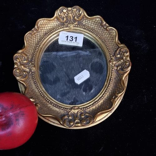 131 - A very pretty vintage small oval mirror housed in an ornate gilt frame.