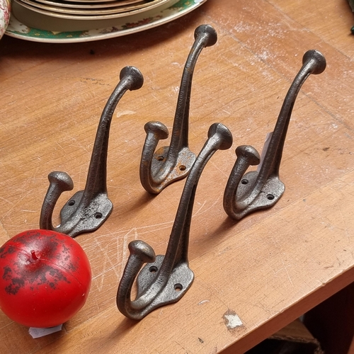 414 - Four cast metal wall mounted coat hooks.