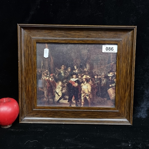 86 - A print of a painting originally by Rembrandt titled 'The Night Watch'. Housed in a wooden frame beh... 