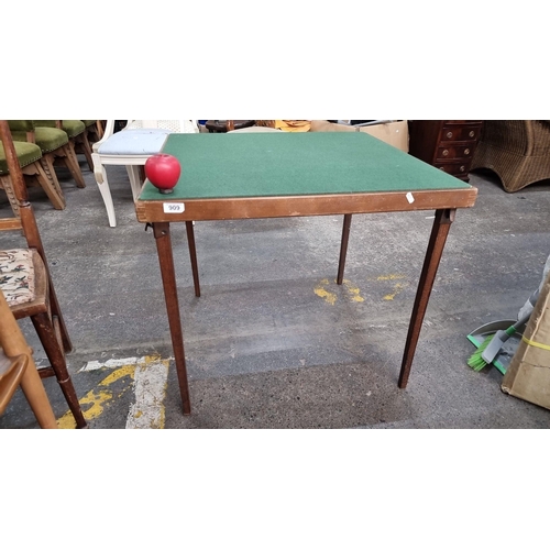 A vintage folding card table with green felt top and wooden legs. Ideal for casual gaming and compact storage.