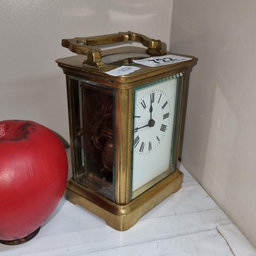 722 - A French antique brass carriage clock with Roman numeral dial and visible inner movement.