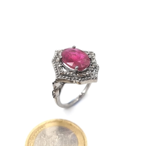 965 - Star Lot : A stunning oval ruby gemstone ring set in a shield design diamond setting mounted in ster... 