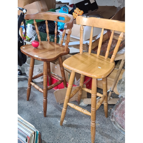 994 - Two tall bar stools with spindle supports to back and footrest, one with a a hand hold and shaped se... 