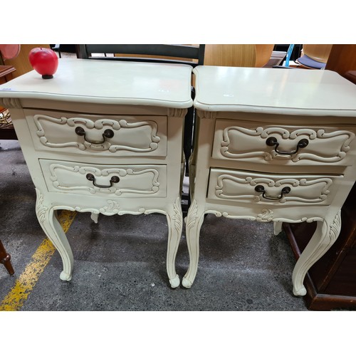 495 - A pair of French style bed side tables / cabinets, in white painted finish with carved detailing.