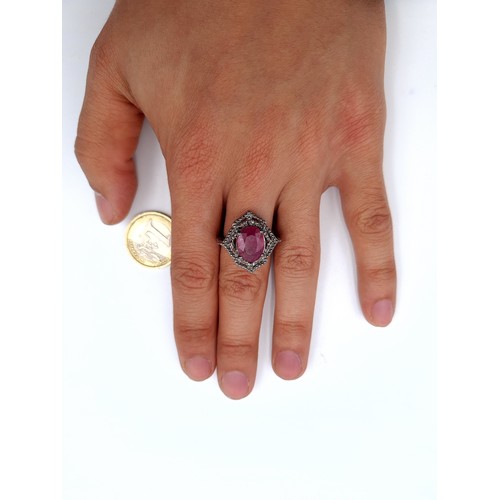 965 - Star Lot : A stunning oval ruby gemstone ring set in a shield design diamond setting mounted in ster... 