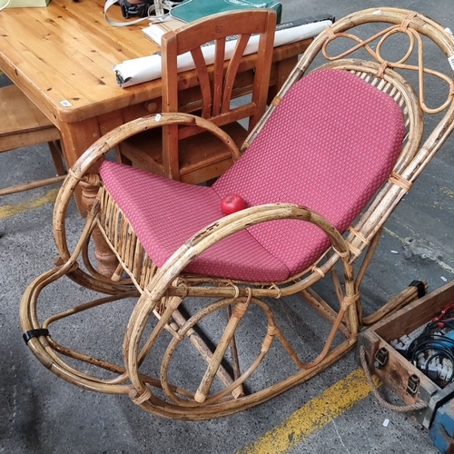 483 - A charming indoor / outdoor Vintage rattan rocking chair with red upholstered cushion.