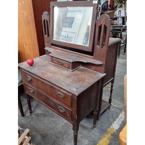 487 - An antique wooden dressing table with tilting beveled mirror. Features three drawers with handles an... 