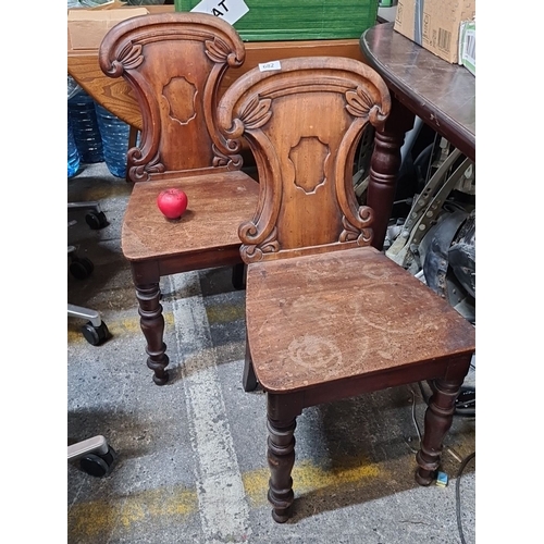 682 - A pair of Victorian hall chairs with shield backs featuring carved designs and lovely turned wood le... 