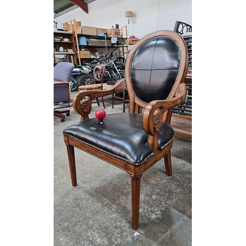 687 - A Louis XVI-style armchair with carved floral accents, upholstered in black leather, featuring brass... 