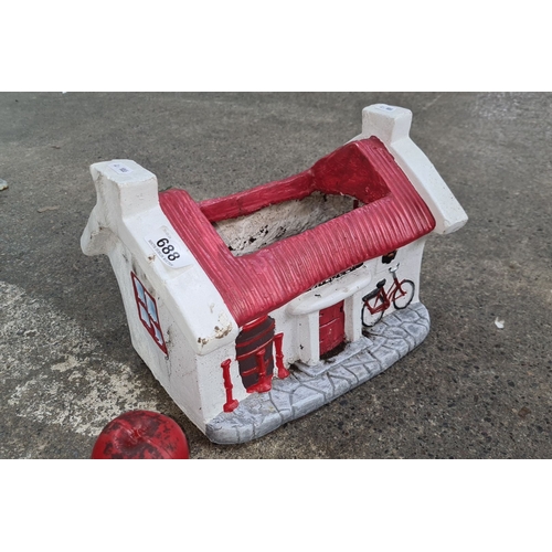 688 - A hand painted reconstituted stone cottage planter with red roof and decorative bicycle motif. Featu... 