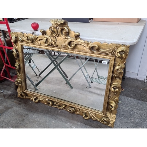 692 - A fab ornate gilded mirror with rococo-style carved wooden frame, featuring intricate scrollwork and... 