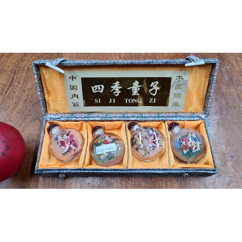 725 - A set of four hand-painted reverse glass snuff bottles with stopper tops in a decorative lined box, ... 