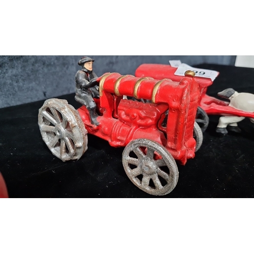 799 - Two vintage cast metal heavy toy vehicles, featuring a red tractor with driver and a red I.C.S. hors... 