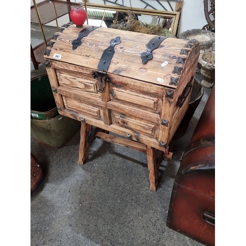 847 - A large rustic footed pine chest with iron hardware and hasp, featuring carved panels and a dome-sha... 