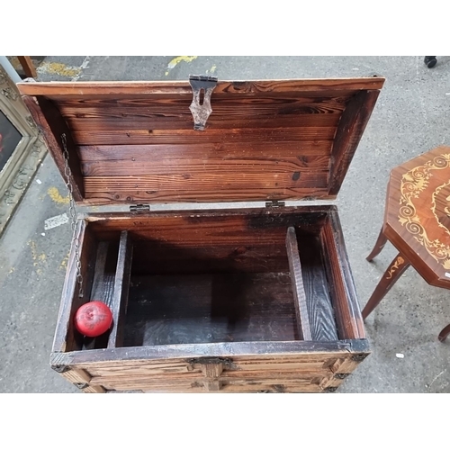 847 - A large rustic footed pine chest with iron hardware and hasp, featuring carved panels and a dome-sha... 