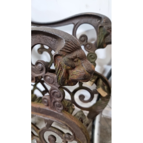 855 - A pair of cast iron bench ends with intricate scrolling design and lion head details.