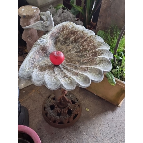 868 - Cast iron birdbath with fish base and scalloped bowl design, featuring aged patina. A charming garde... 