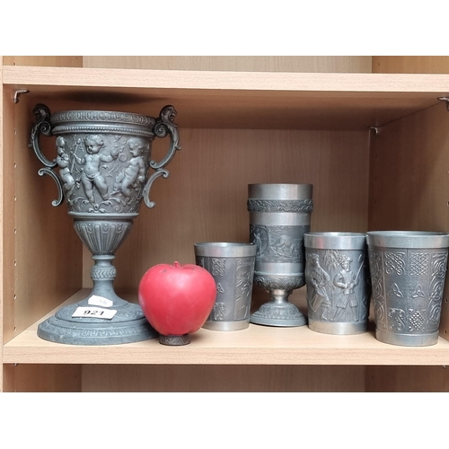 921 - Five pewter examples including four drinking cups along with a double handled chalice. All feature o... 