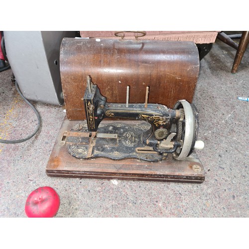 961 - An beautiful antique sewing machine with original hand crank and casing.