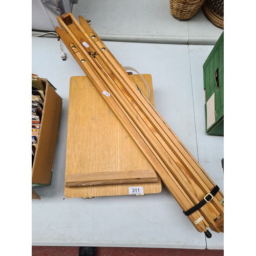 311 - An artists wooden tripod easel stand, along with a table top easel storage tool box containing some ... 