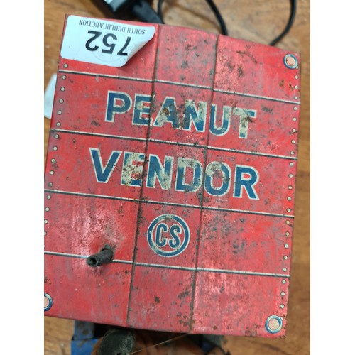 752 - A vintage tin wind-up toy featuring a peanut vendor with dog figure. Mechanical components including... 