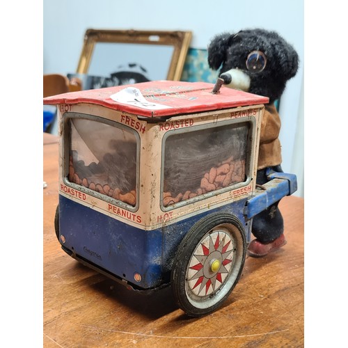 752 - A vintage tin wind-up toy featuring a peanut vendor with dog figure. Mechanical components including... 