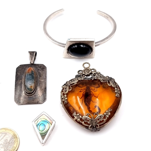 43 - Four items consisting of an antique sterling silver heart shaped amber pendant set with a scorpion i... 