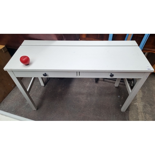 865 - A solid white wooden desk with two drawers, featuring black knobs and striped patterned drawer inter... 