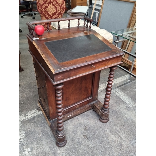 869 - A Victorian mahogany Davenport desk featuring a sloped writing surface, turned supports, and interio... 