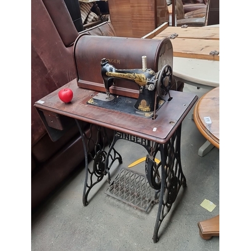 877 - An antique Singer treadle sewing machine with wooden cabinet, detailed metalwork base, foot peddle a... 