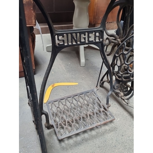 877 - An antique Singer treadle sewing machine with wooden cabinet, detailed metalwork base, foot peddle a... 