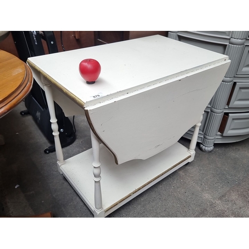 879 - A white-painted drop-leaf side table with turned legs and lower shelf, featuring casters for easy mo... 