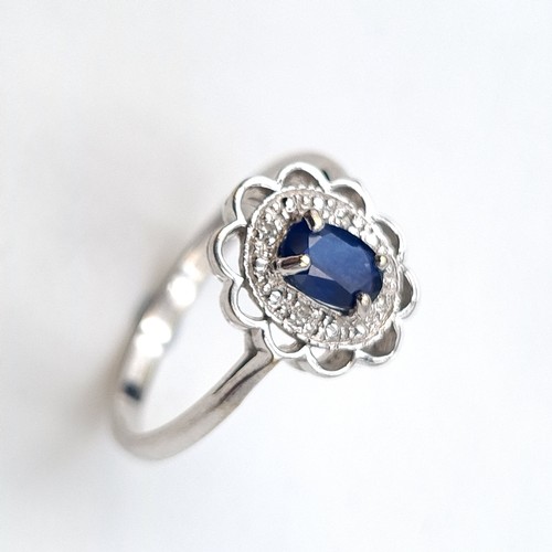 936 - An 18 carat gold blue sapphire gemstone ring set with diamond surround. Ring size - N. Weight - 2.76... 