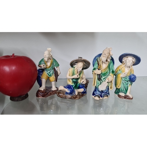 672 - Four hand-painted ceramic figurines depicting elder figures in traditional attire, each adorned with... 