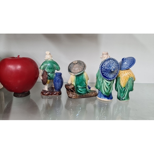672 - Four hand-painted ceramic figurines depicting elder figures in traditional attire, each adorned with... 