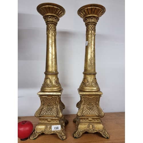 158 - An elegant pair of tall gold toned candle holders.