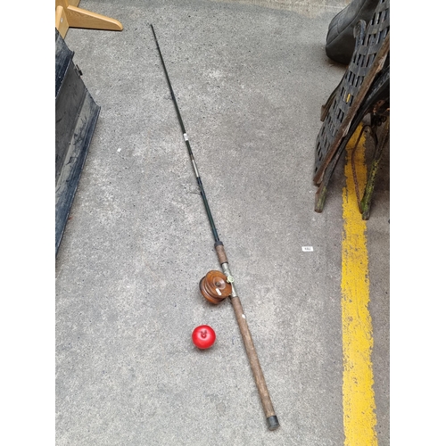 293 - A fantastic vintage fishing rod with wooden fly reel and Bakelite and brass handle.