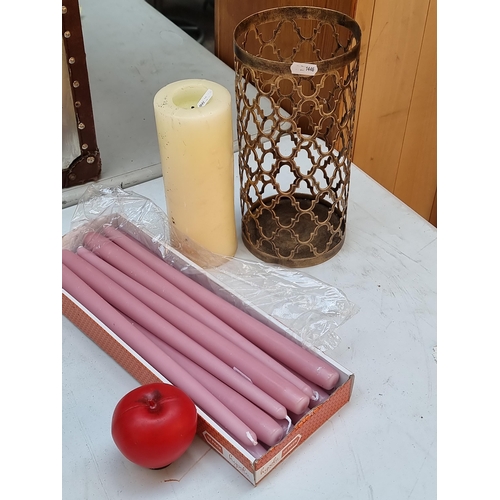 309 - A selection of household items including a box of long taper pale pink candles. One cream wax pillar... 