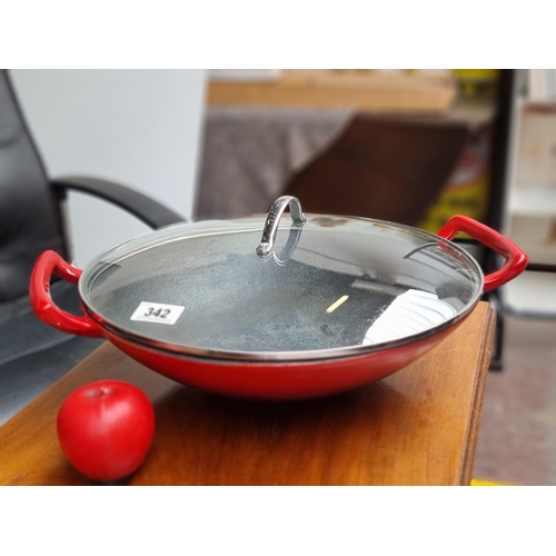 342 - A large heavy cast iron wok complete with glass lid in a vibrant shade of red.